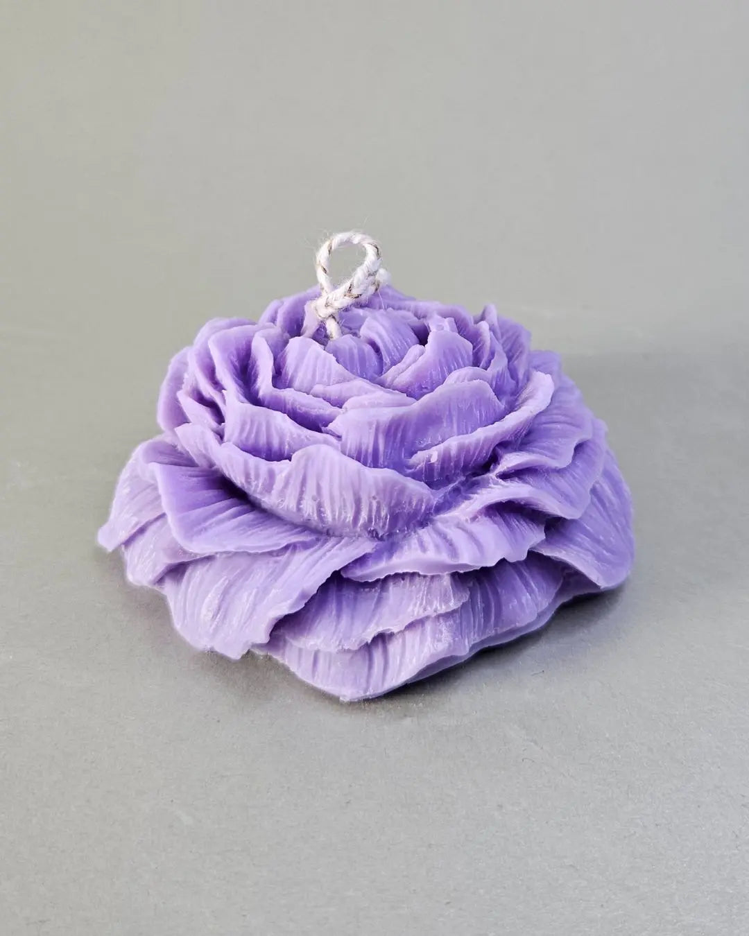 Handgefertigte Pfingstblumen-Kerze aus Rapswachs in Lila, Nahaufnahme.