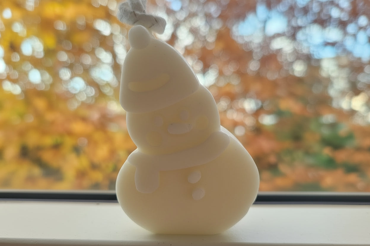 Rote Schneemann-Dekofigur mit Mütze und Schal vor herbstlichem Fensterhintergrund