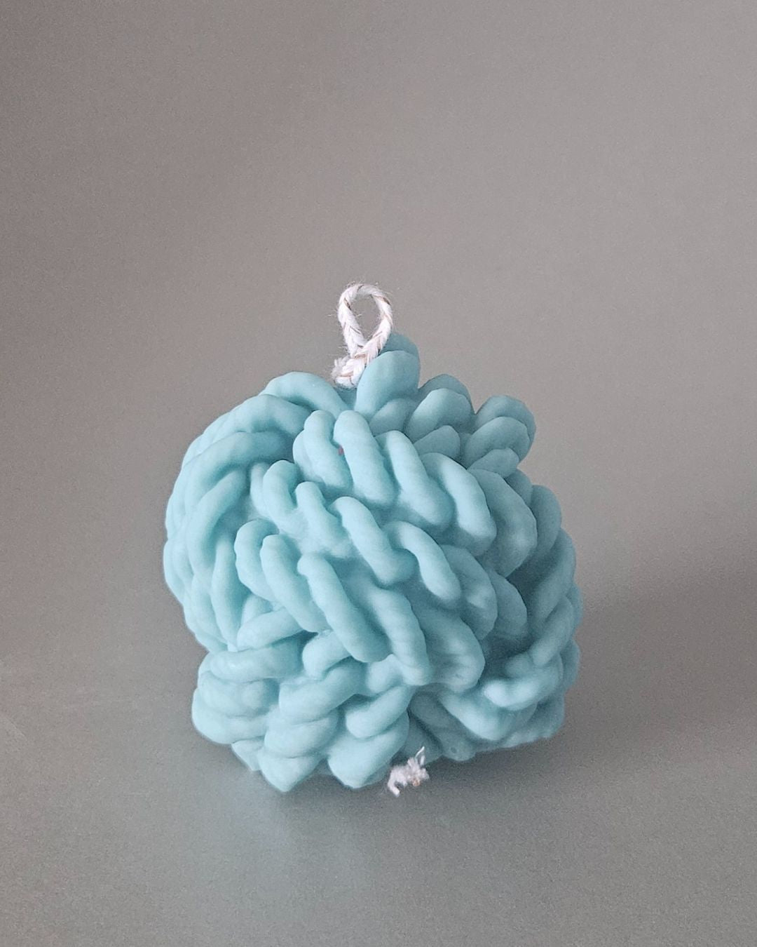 Handgemachte Wollknäuel-Kerze aus Rapswachs in Türkis – kreative Designkerze, nachhaltig hergestellt in der Schweiz.